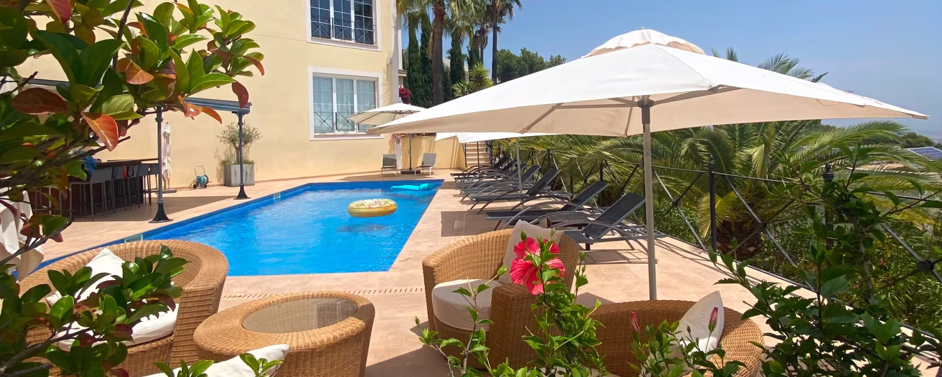 Relaxing outdoor space at Holiday Home Mallorca with blue rectangular pool, sun loungers, wicker furniture, and palm trees